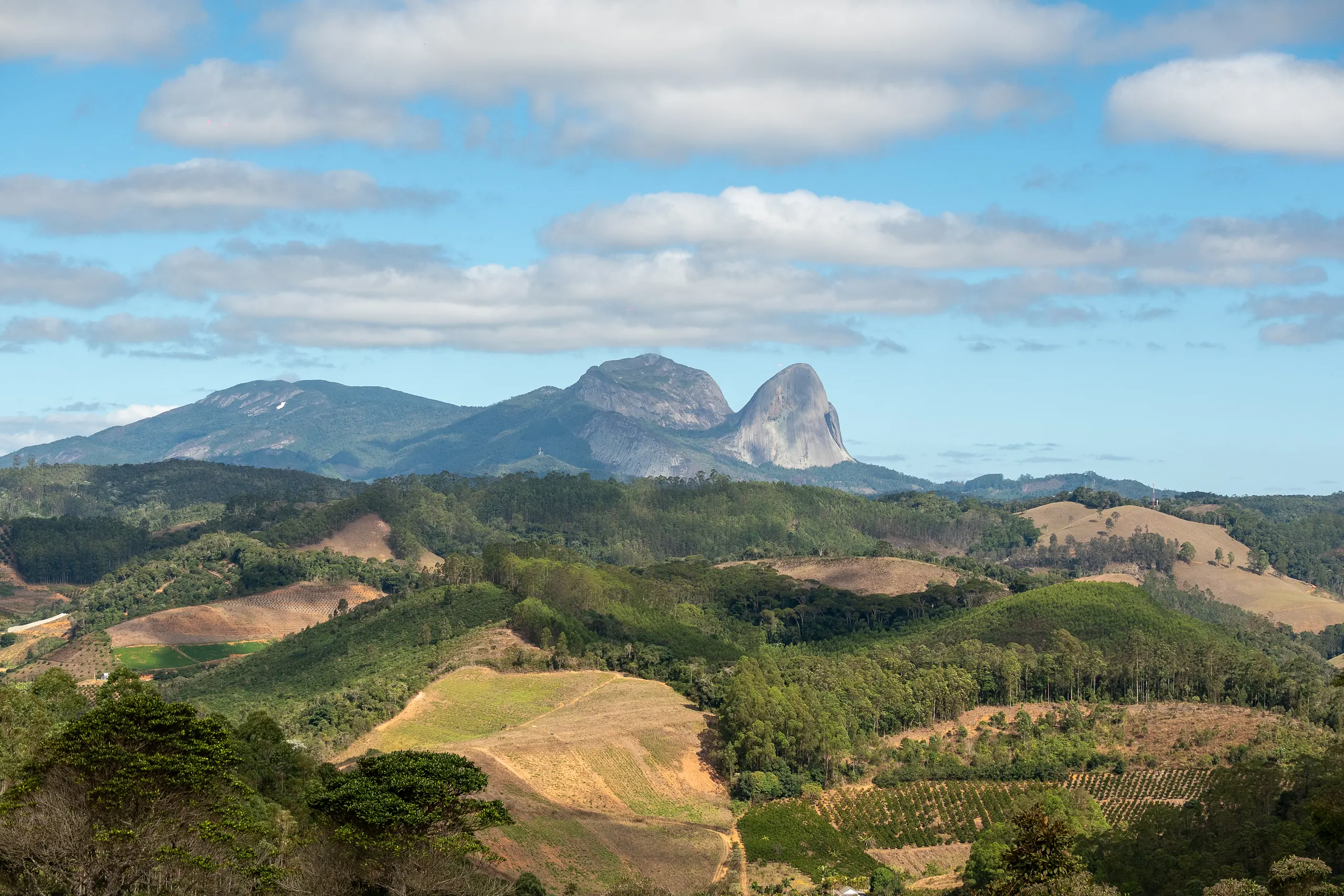 Vale da serra capixaba com a Pedra Azul ao fundo, sob céu aberto